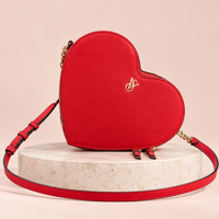 Cartera corazón Victoria’s Secret roja con logo dorado y correa larga, vista frontal.