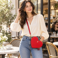 Modelo con blusa blanca y jeans llevando cruzada la cartera corazón Victoria’s Secret roja; imagen ilustrativa.
